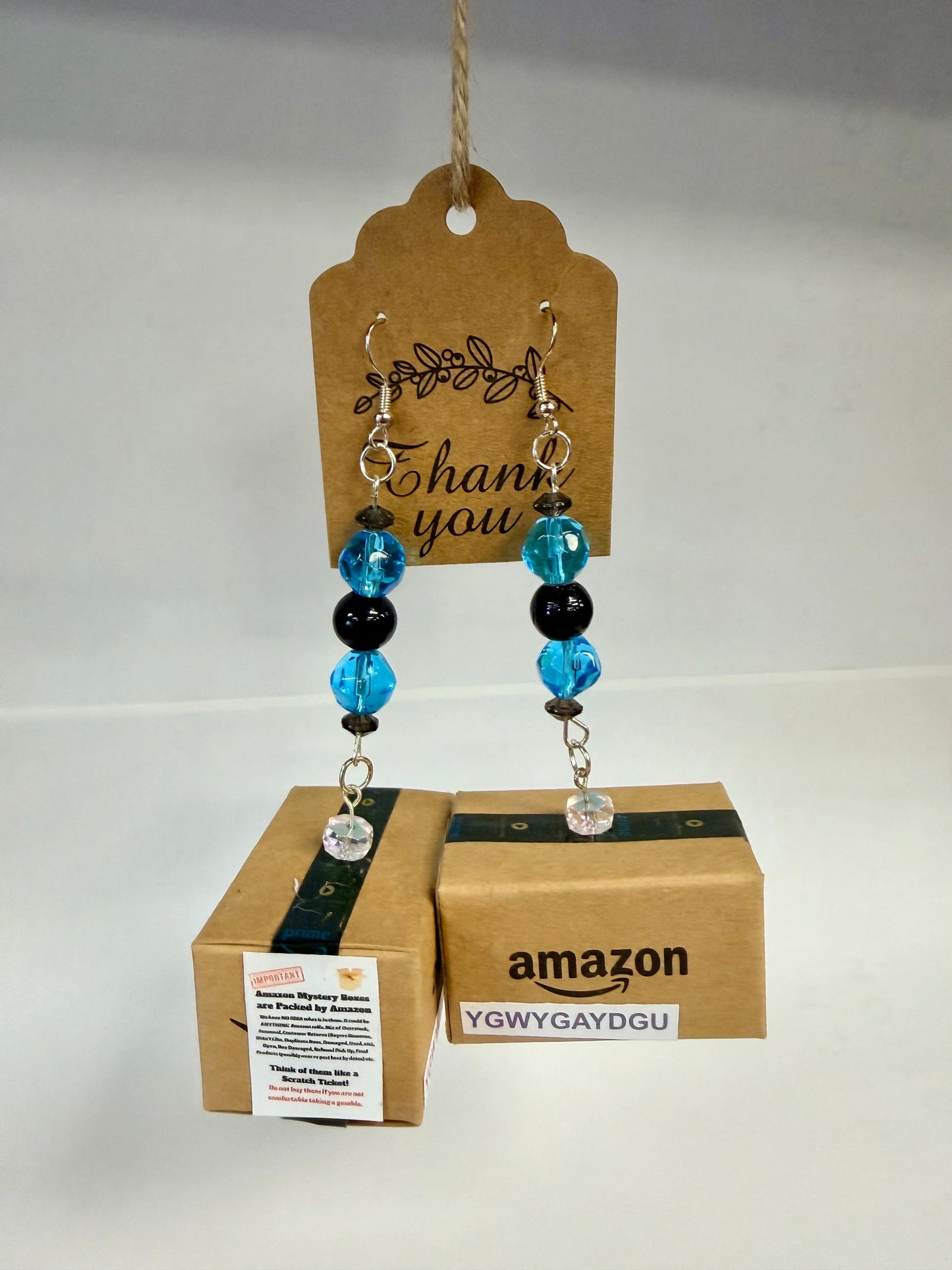 Handcrafted miniature Amazon mystery box earrings close-up